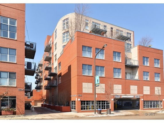 Front view of a multi-story brick apartment building with balconies.