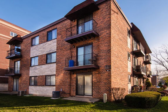 Front view of a multi-story brick apartment building with balconies.