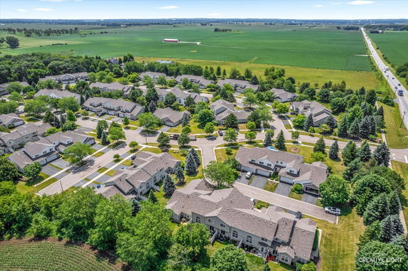 Panoramic view of a residential neighborhood surrounded by green fields and trees.
