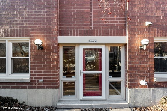 Front view of a brick building entrance with glass door and windows.