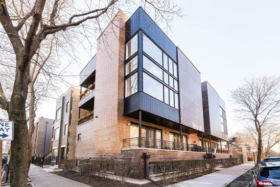 Front view of a modern multi-story brick building with large windows.