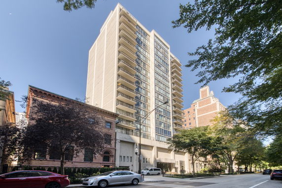 Front view of a tall residential building with balconies, located on a city street.