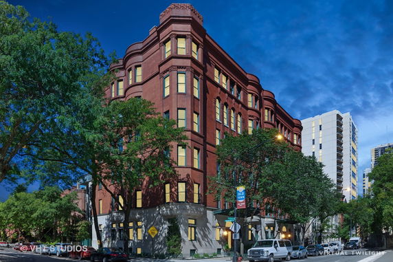 Front view of a multi-story red brick building with multiple windows and decorative architectural details.