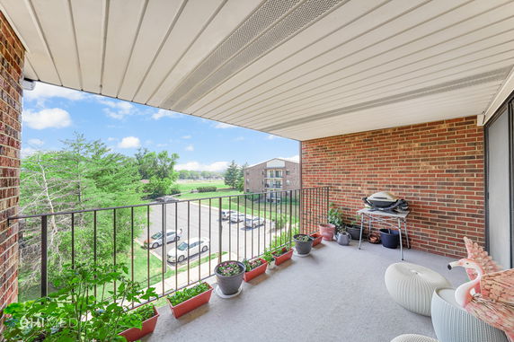 Balcony with potted plants and a view of surrounding buildings and greenery.
