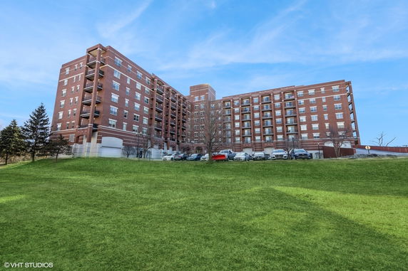 Front view of a large multi-story apartment building with balconies and brick exterior.