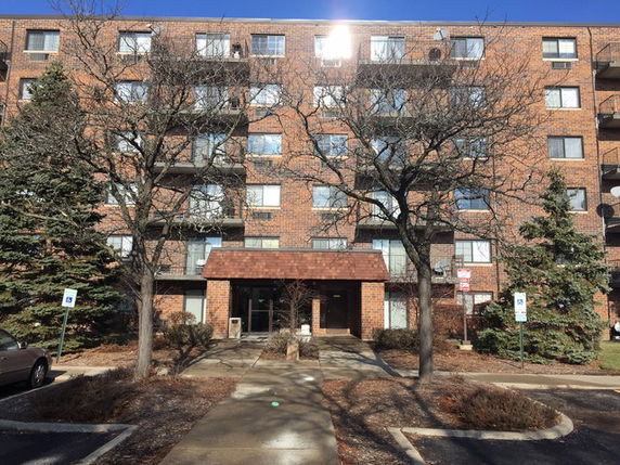 Front view of a multi-story brick apartment building with balconies.