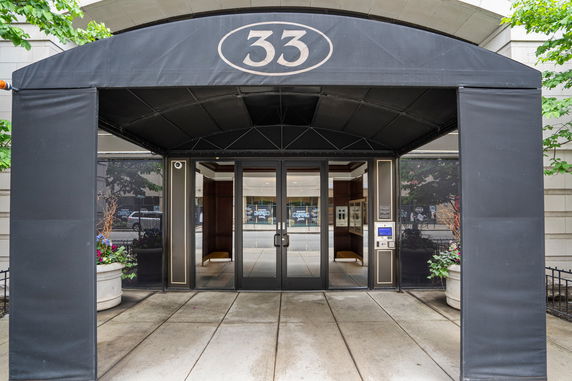 Front entrance of a building with a black awning and glass doors.