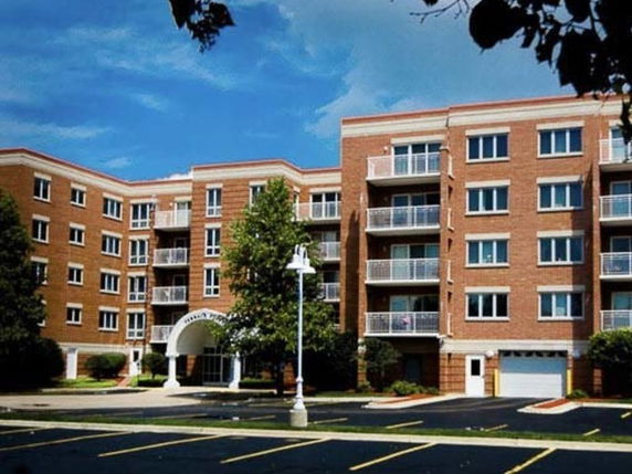 Front view of a multi-story apartment building with a brick facade and balconies.
