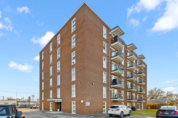 Front view of a multi-story brick apartment building with balconies.