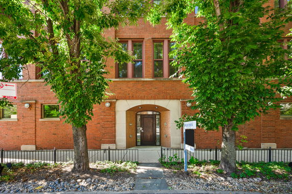 Front view of a brick building with a central entrance and multiple windows.
