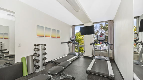 Indoor gym area with exercise equipment, including treadmills and weights.