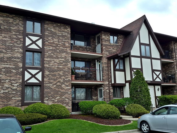 Front view of a multi-story brick apartment building with balconies.