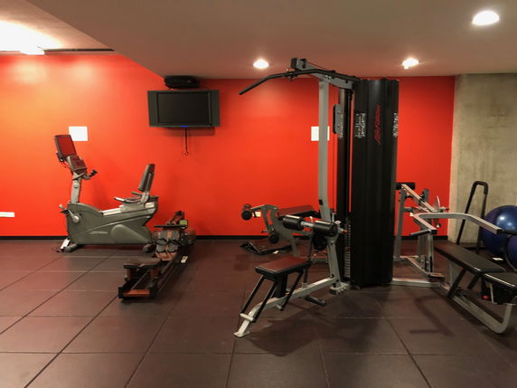 Indoor gym area with exercise equipment and a red wall.