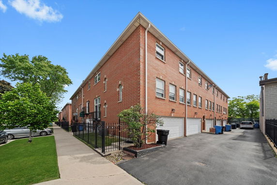 Front view of a multi-story brick residential building with garages.