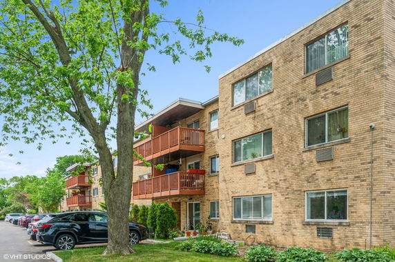 Front view of a three-story brick apartment building with balconies.