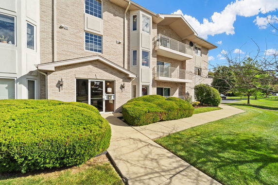 Front view of a multi-story building with balconies and a small entrance area.