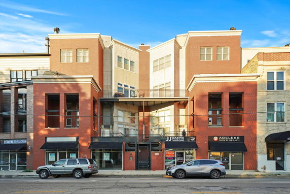 Front view of a multi-story commercial and residential building with various shopfronts on the ground level.