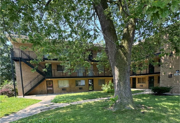 Front view of a two-story apartment building with outdoor staircases and balconies.