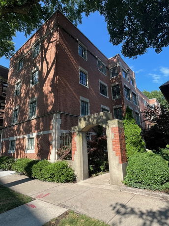Front view of a multi-story brick building with an arched entrance.