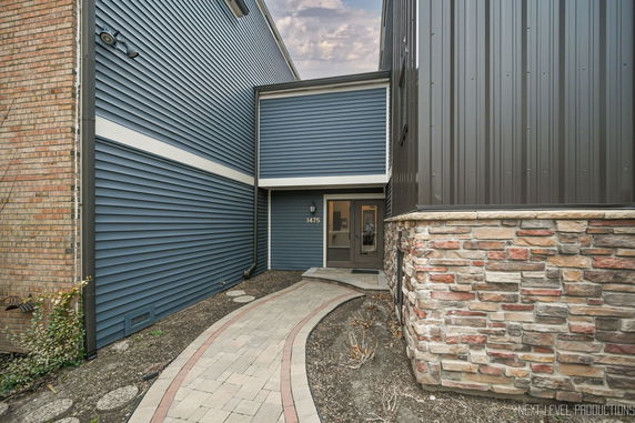 Entrance view of a building with blue siding and a stone facade.