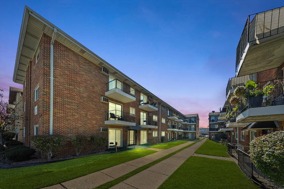 Front view of a three-story apartment building with balconies and brick exterior.