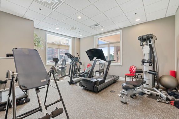 Room equipped with exercise machines including a treadmill and stationary bikes.