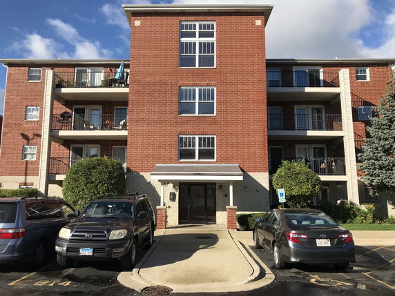Front view of a multi-story brick apartment building with balconies.