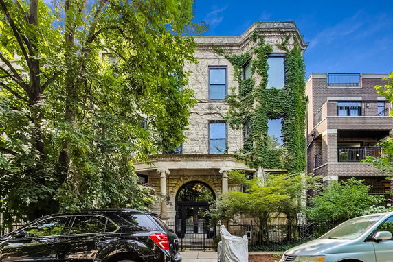 Front view of a three-story building with ivy-covered walls and an arched entrance.