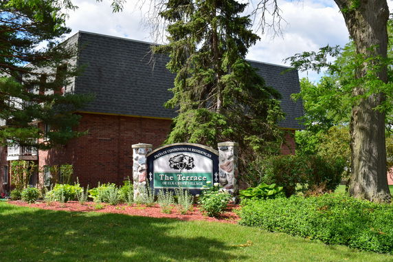 Front view of a brick condominium building with a sloped roof.
