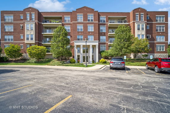 Front view of a multi-story brick apartment building with balconies.