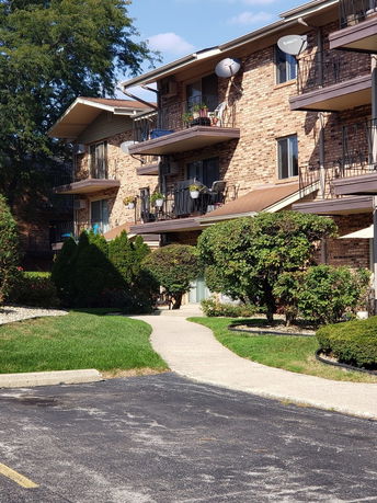 Front view of a multi-story brick apartment building with balconies and satellite dishes.