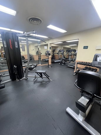 Indoor gym area with exercise equipment including treadmills, weights, and a multi-gym machine.