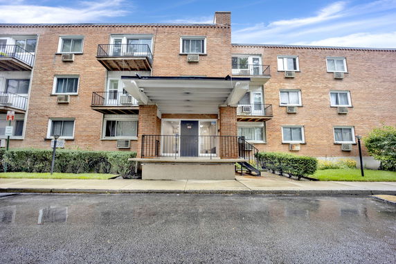Front view of a multi-story brick apartment building with balconies.