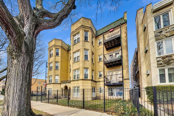 Front view of a multi-story residential building with balconies and bay windows.
