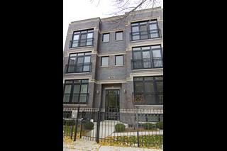 Front view of a three-story building with large windows and a gated entry.