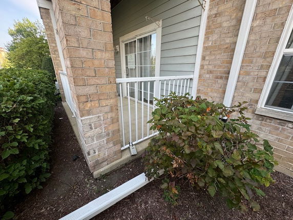 Front view of a building with a small balcony and sliding glass door.
