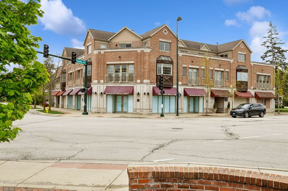 Front view of a three-story commercial building with brick exterior and large windows.