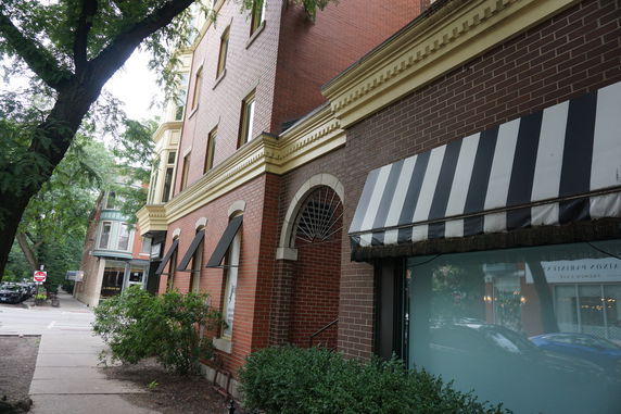 Front view of a multi-story building with striped awning and brick exterior.
