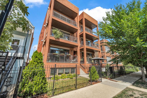 Front view of a multi-story brick apartment building with balconies.
