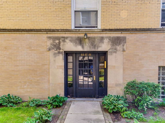 Front view of a building entrance with a dark door and brick exterior.