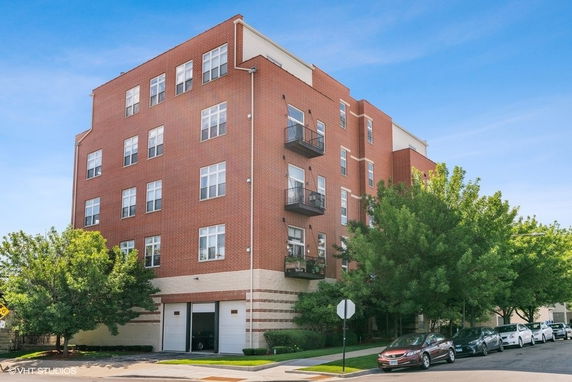 Front view of a multi-story brick apartment building with balconies.