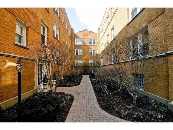 Front view of a multi-story brick apartment building with a walkway.