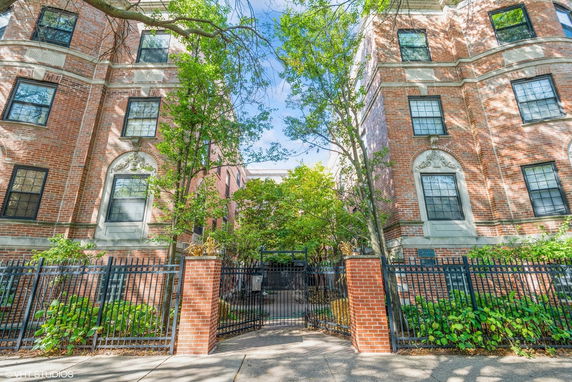 Front view of a brick apartment building with decorative architectural details and a gated entrance.