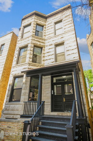 Front view of a multi-story house with a stone facade and black entrance.
