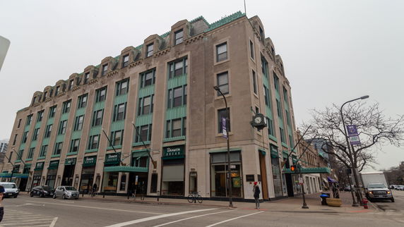 Front view of a multi-story commercial building with large windows and a street clock.