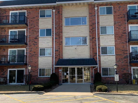 Front view of a multi-story brick apartment building with balconies and entrance.