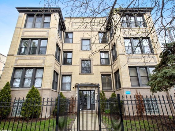 Front view of a multi-story brick apartment building with large windows.