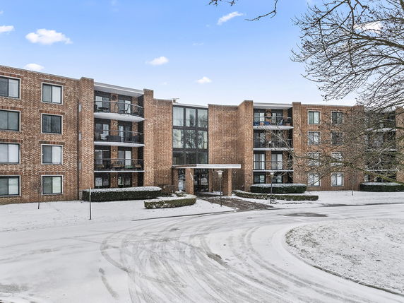Front view of a multi-story brick apartment building in snowy conditions.