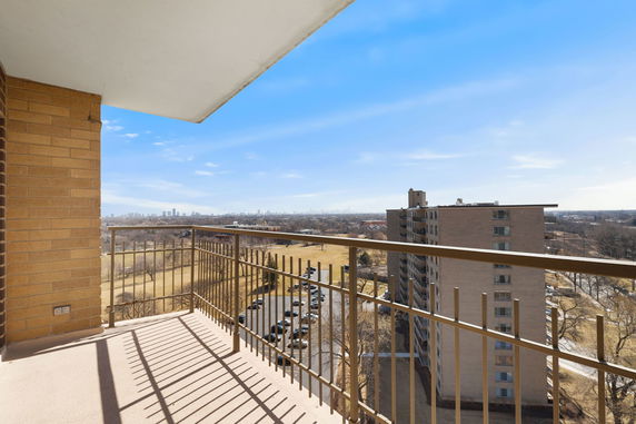 View from a balcony overlooking a cityscape with high-rise buildings and open fields.