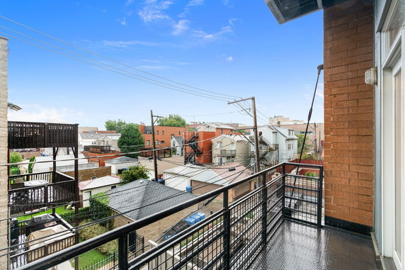 Balcony view overlooking residential rooftops and surrounding area.